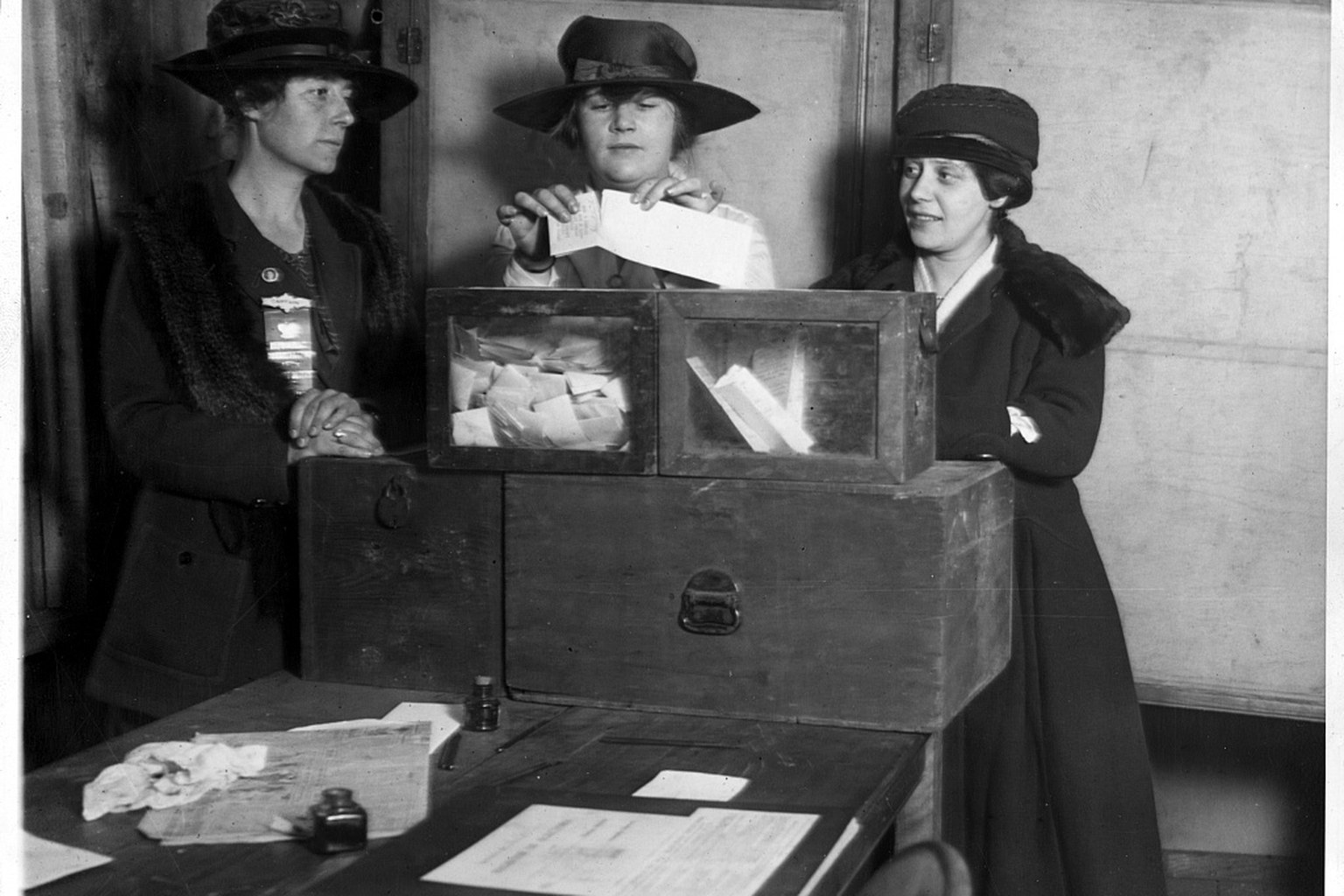 Historic photograph of three women casting ballots at a polling place