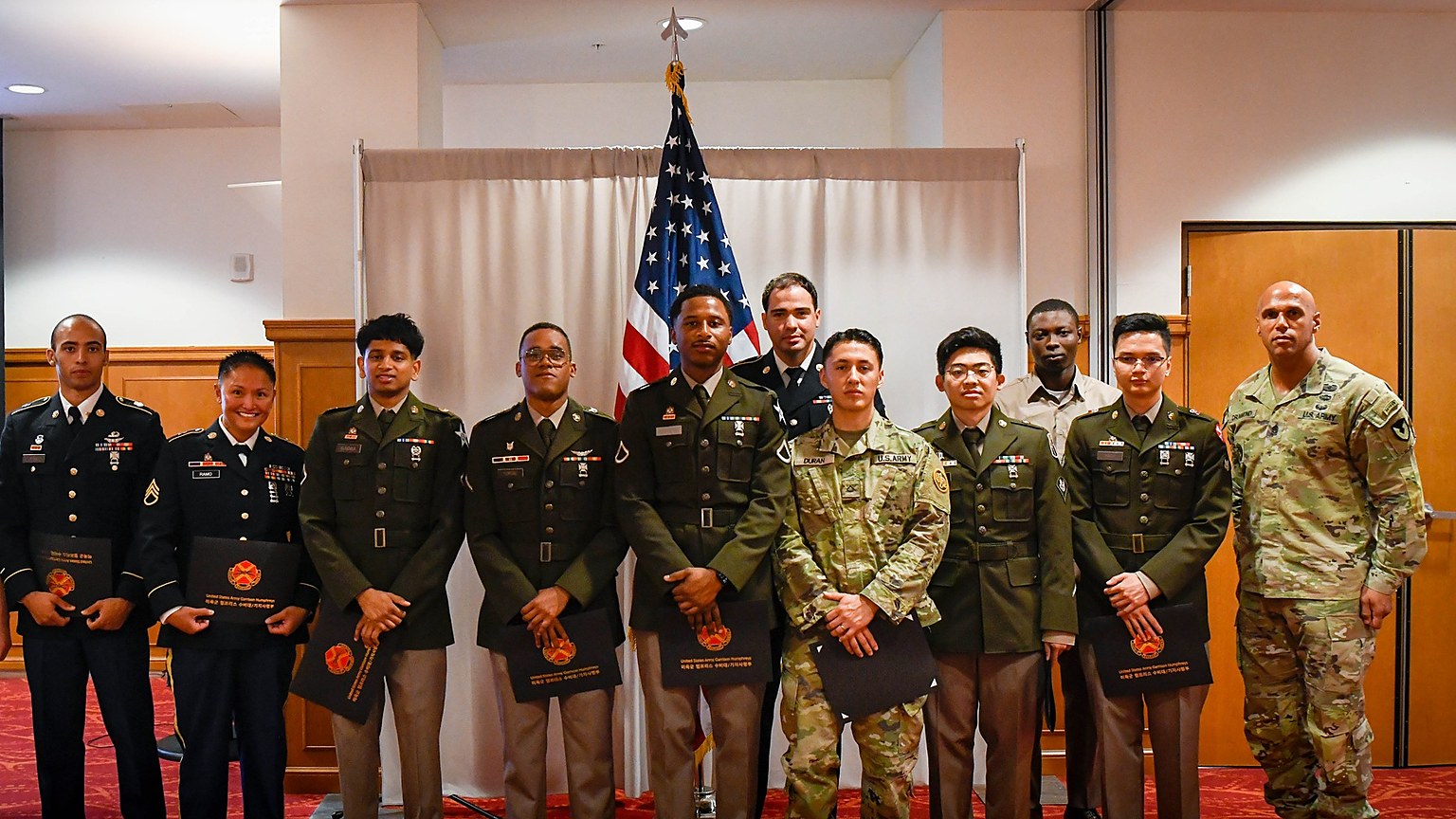Service members pose with naturalization certificates after a USCIS oath ceremony
