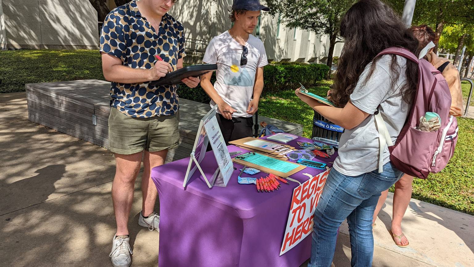 Students sign up at an outdoor voter registration table on a college campus