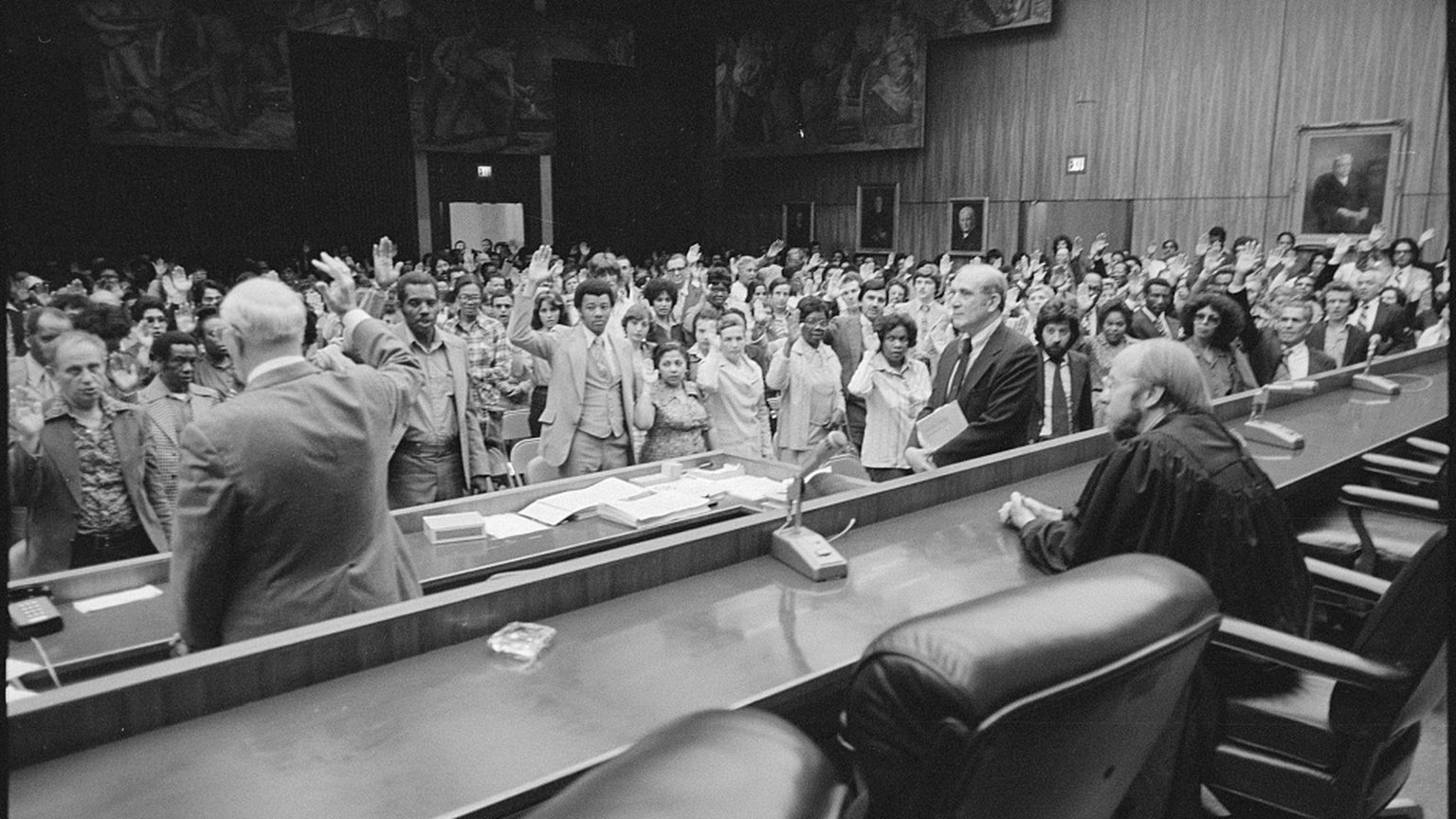 People raise their right hands during a naturalization oath ceremony